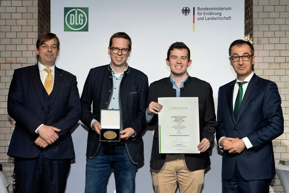 Bundesminister Cem Özdemir (rechts) überreicht gemeinsam mit DLG-Präsident Hubertus Pae-tow (links) Urkunde und Medaille an Eike-Henrik Wagner und Florian Saggau. Foto: DLG, Christian Lietzmann