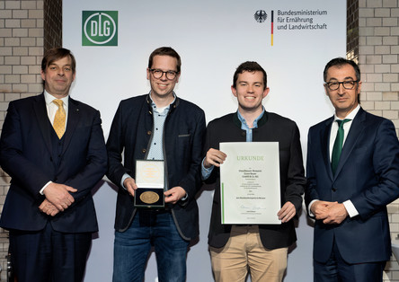 Bundesminister Cem Özdemir (rechts) überreicht gemeinsam mit DLG-Präsident Hubertus Pae-tow (links) Urkunde und Medaille an Eike-Henrik Wagner und Florian Saggau. Foto: DLG, Christian Lietzmann